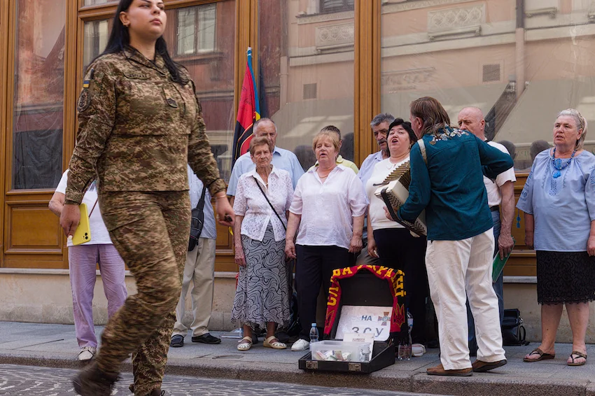 A female Ukrainian soldier passes by a choir singing in central Lviv.